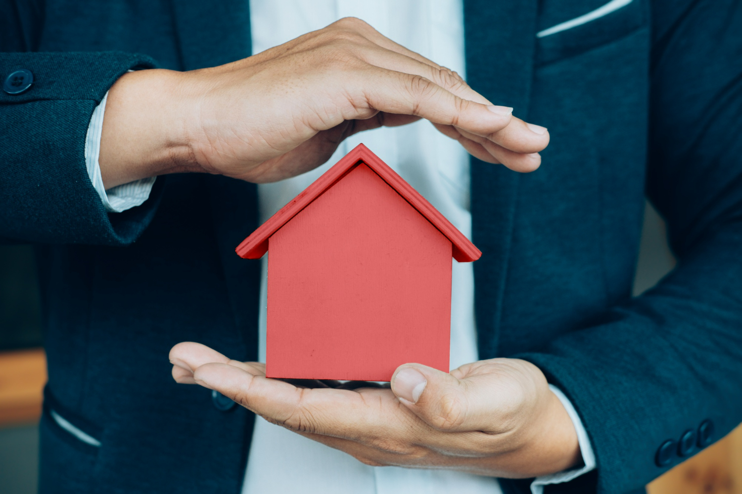 Homme protégeant une maison entre ses mains 